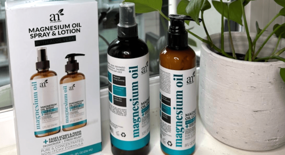 ArtNaturals Magnesium Oil spray and lotion bottles with their box on a windowsill near a plant