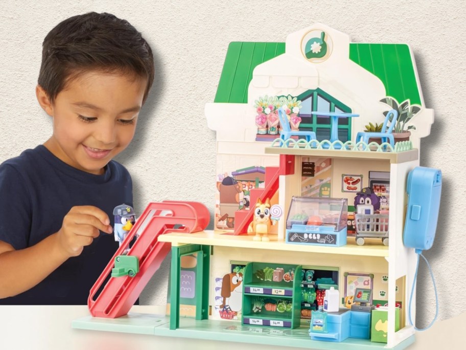 little boy playing with a Bluey and Bingo Supermarket Playset