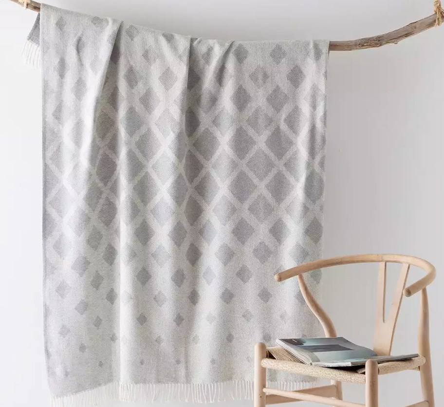 grey throw hanging from a branch near a chair