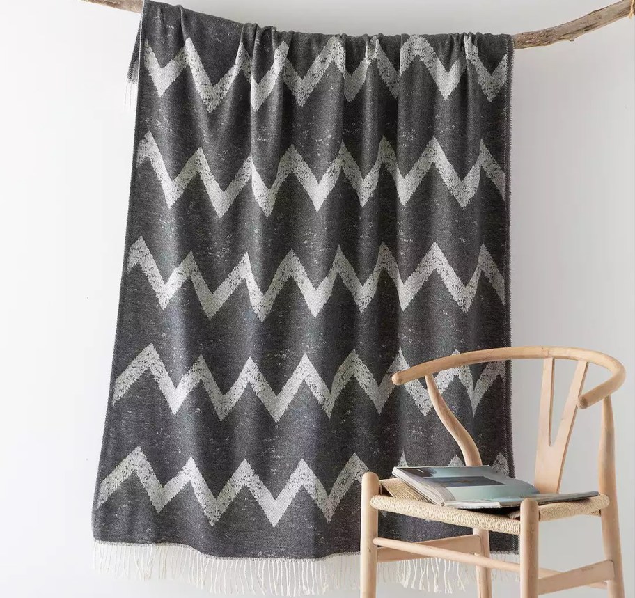 grey throw hanging from a branch near a chair
