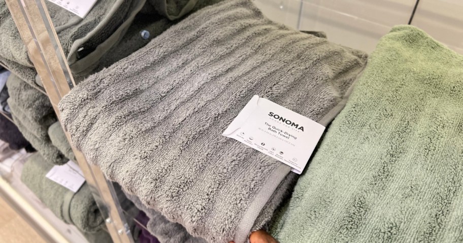 hand pulling a ribbed bath towel off a store shelf