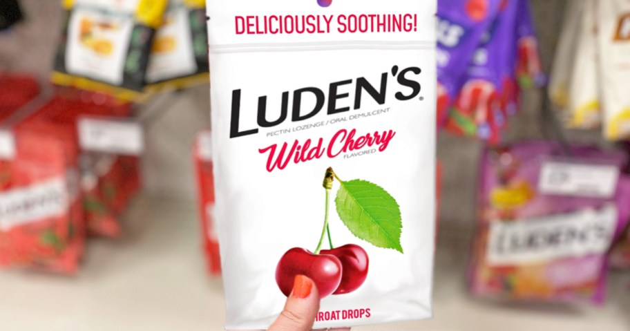 hand holding a white bag of Luden&rsquo;s Wild Cherry Throat Drops in store