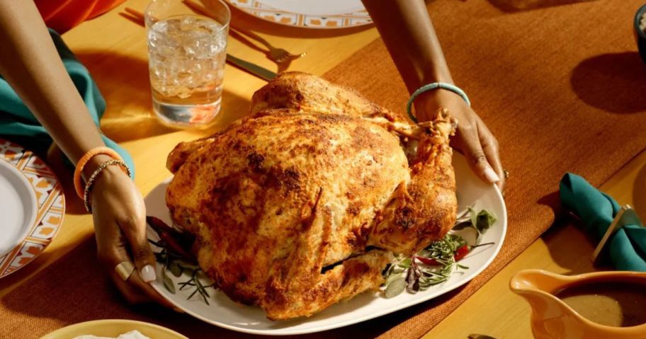 A woman serving a Popeyes Cajun Turkey on a platter