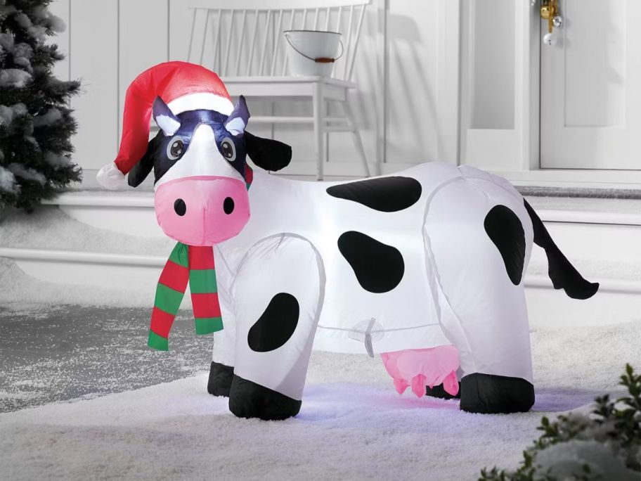 Inflatable Cow with a Santa hat on in front of a house