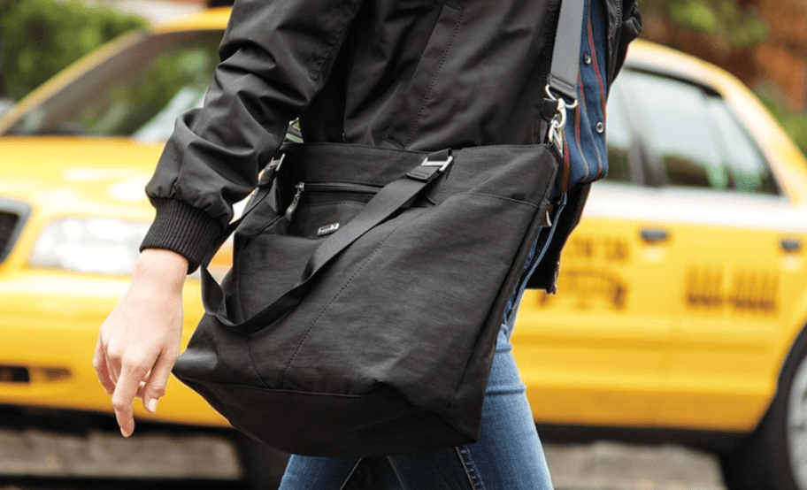 woman walking while carrying a black tote bag