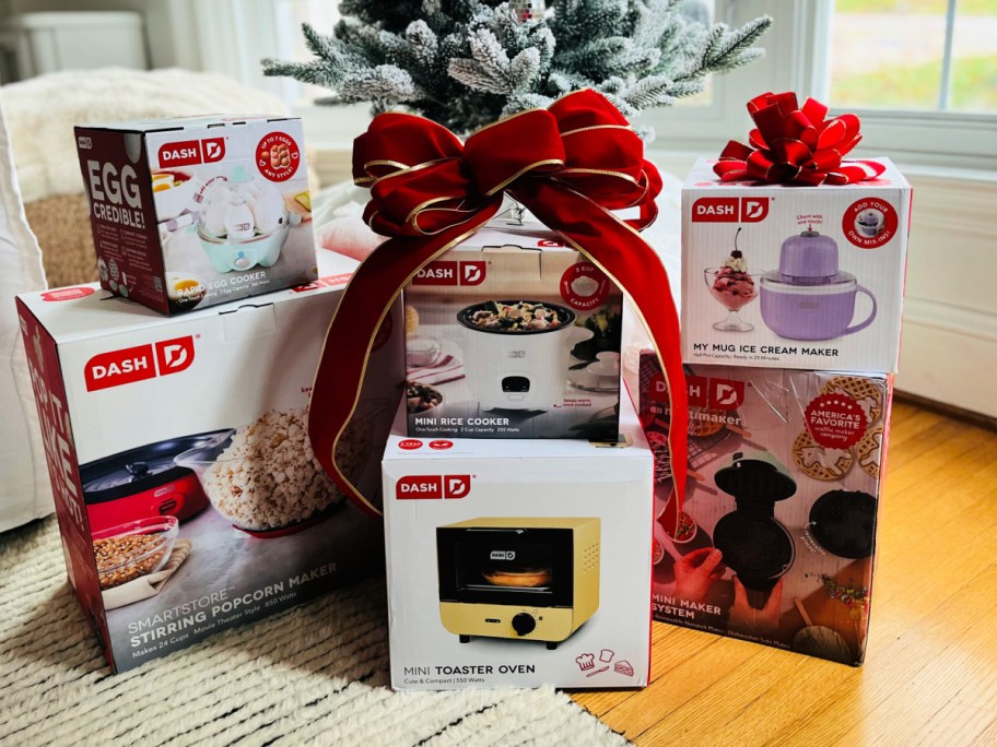 boxes of dash mini appliances with christmas bow in front of christmas tree