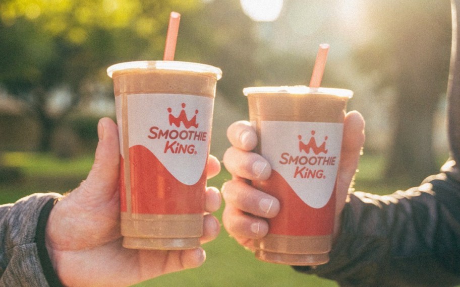 two hands holding up apple and pecan smoothies