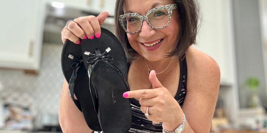 woman holding a pair of black sandals 