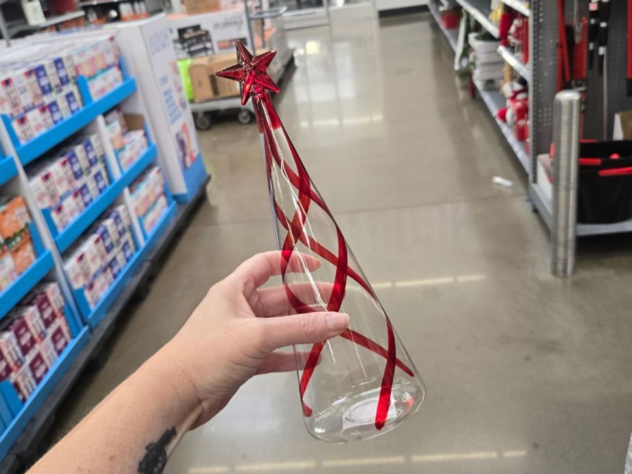 clear Glass Christmas Tree with red wavy stripes around it in hand in store