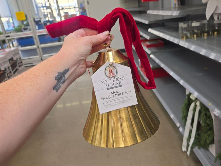 hand holding My Texas House Metal Hanging Bell Decor in store