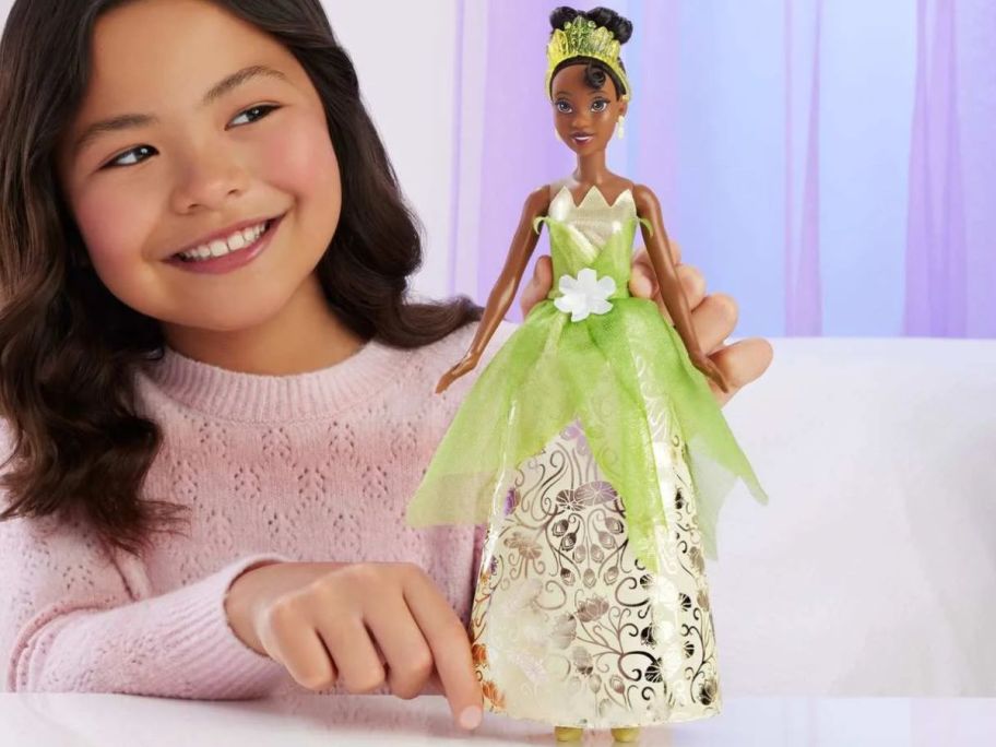 girl holding Disney Princess Enchanted Stories Tiana Fashion Doll