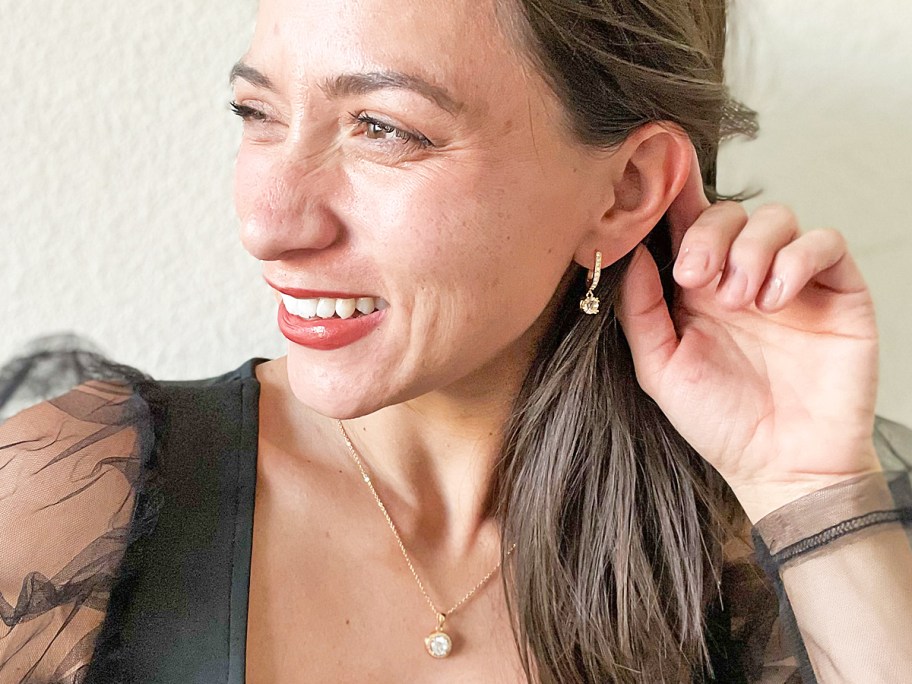 woman in black top showing matching earrings and necklace