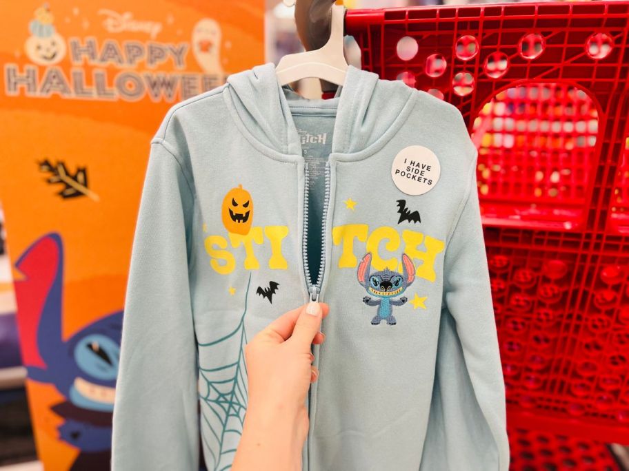 A person zipping up a blue sweatshirt with Stitch on it 
