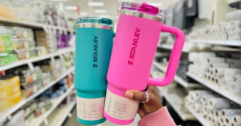 hand holding a teal color and a bright pink color Stanley 30oz tumbler