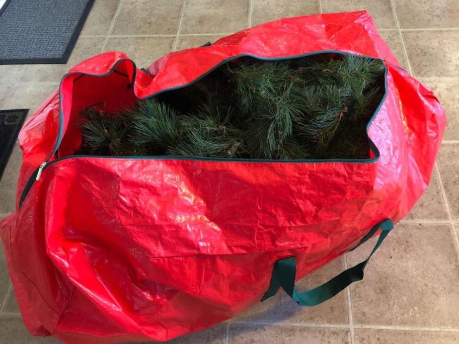 A red Christmas Tree storage bag with a tree inside of it 