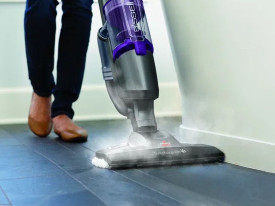 person using bissell steam mop on floor with steam rising from it