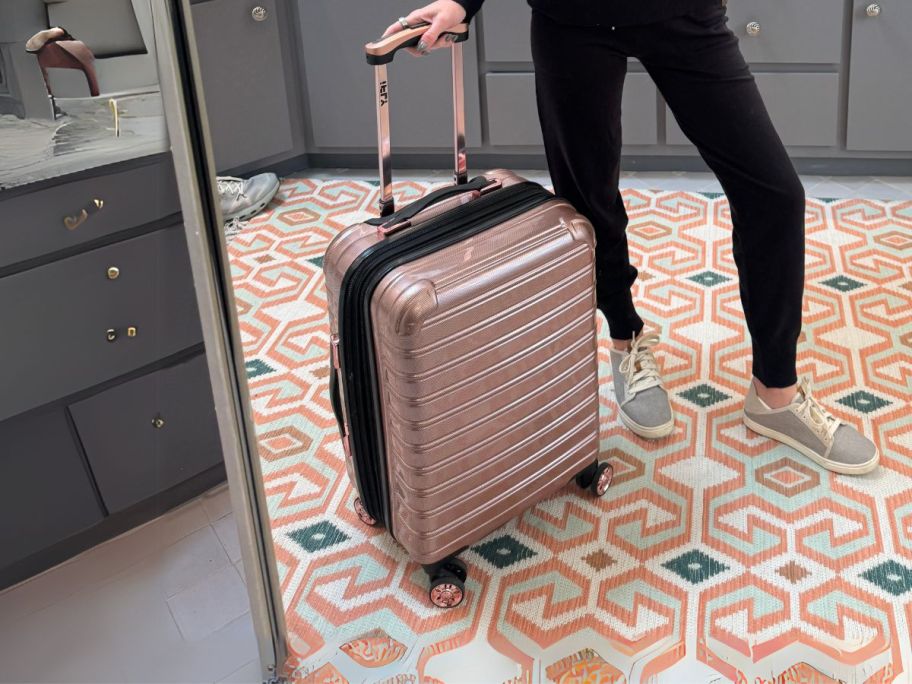 woman holding iFLY luggage handle in mirror in bathroom