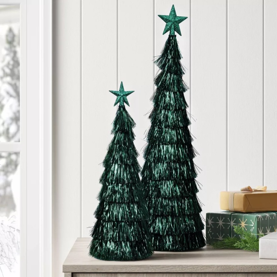 two green tinsel Christmas trees on a table
