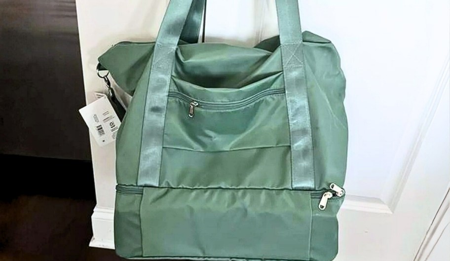 a green weekend duffle bag hanging on a doorknob