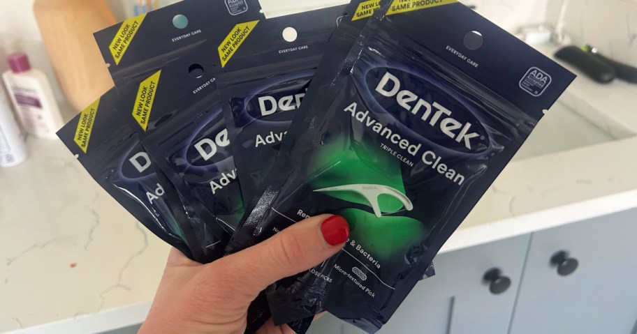 Woman holding up six packages of Dentek flossers