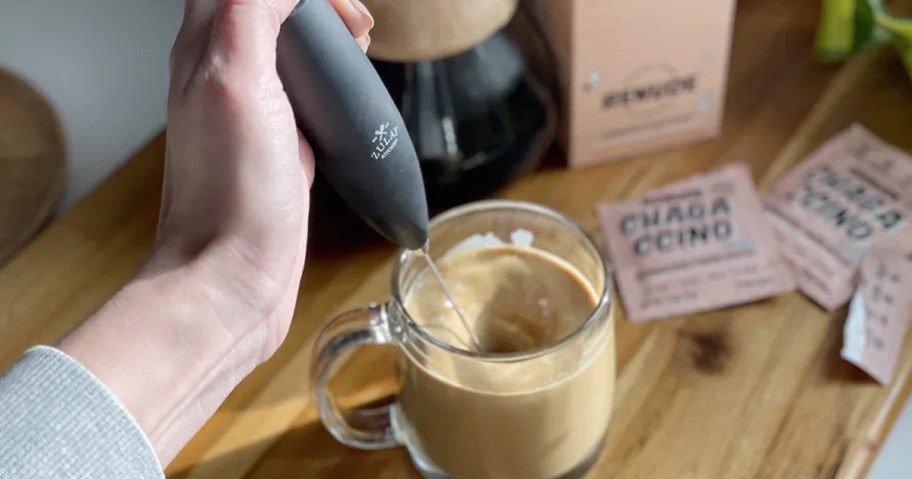 person using Zulay Milk Frother in a cup of coffee