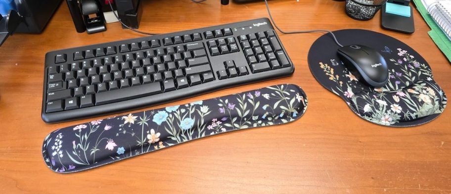 close up of floral mouse and wrist pad for keyboard on wood desk