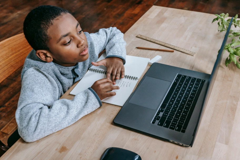 child sitting at desk on laptop