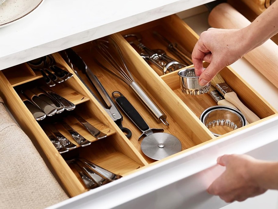 hand grabbing cookie cutter from bamboo organizer inside drawer