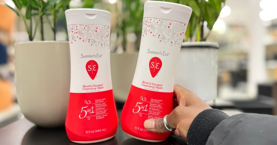 hand grabbing white and red bottle of Summer's Eve Cleansing Wash