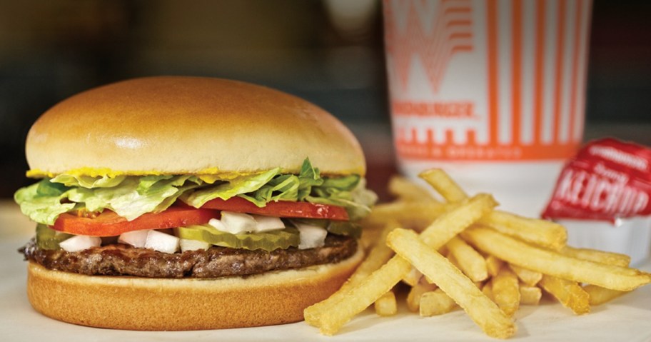 Whataburger burger next to fries, ketchup, and a drink