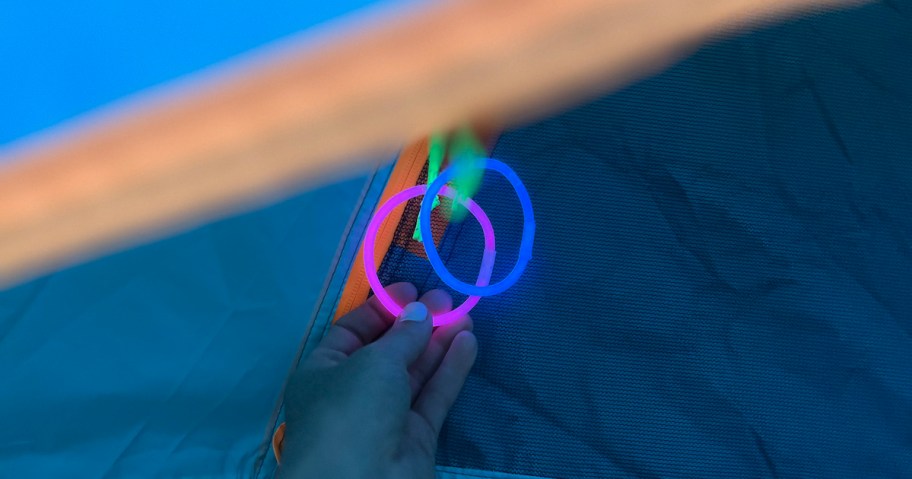 hand holding two glow sticks on tent door