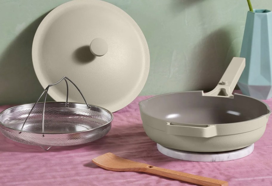 beige always pan with strainer, lid and spatula on table