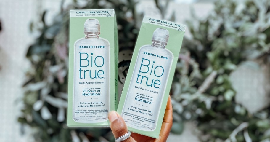 person holding two bottles of biotrue contact solution in store
