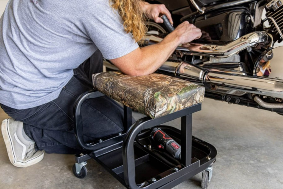 man leaning on a Mossy Oak Rolling Mechanic Stool