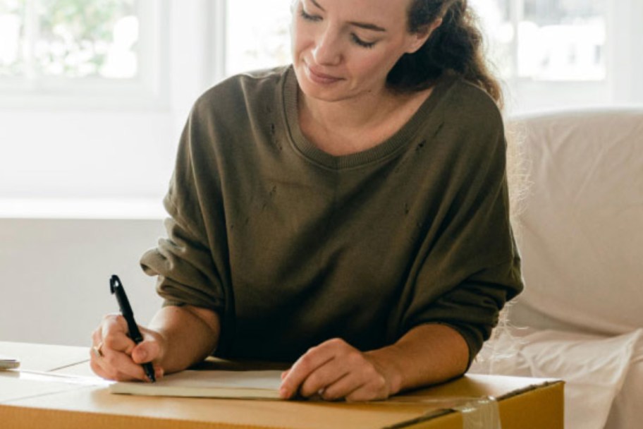 woman writing on cardboard box