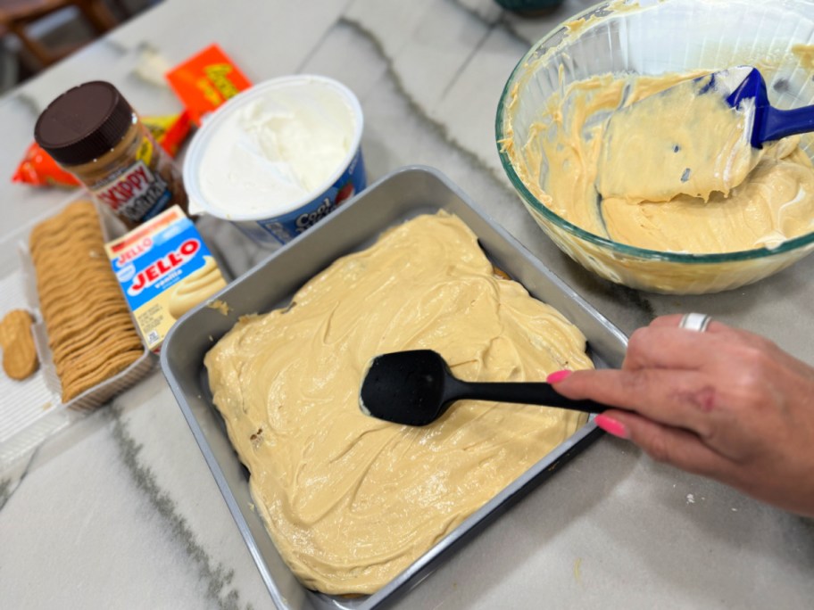 spreading first layer of filling on nutter butter cake 