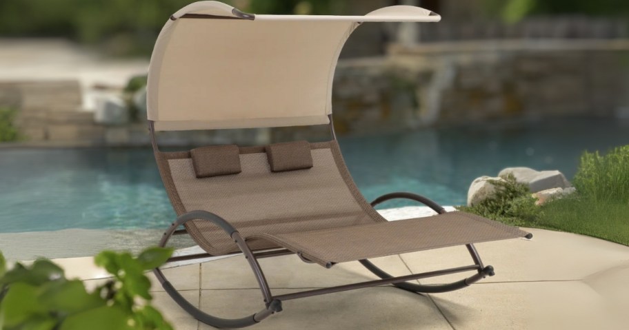 tan and beige colored double chaise lounger by pool
