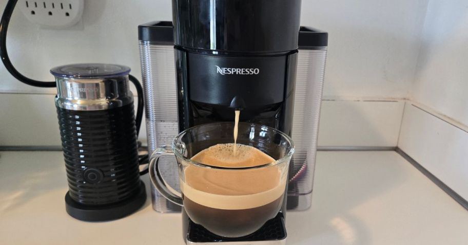 Nespresso Evoluo Coffee & Espresso Maker on counter brewing espresso into clear coffee cup
