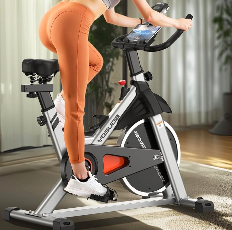woman in orange leggings on a stationary bike