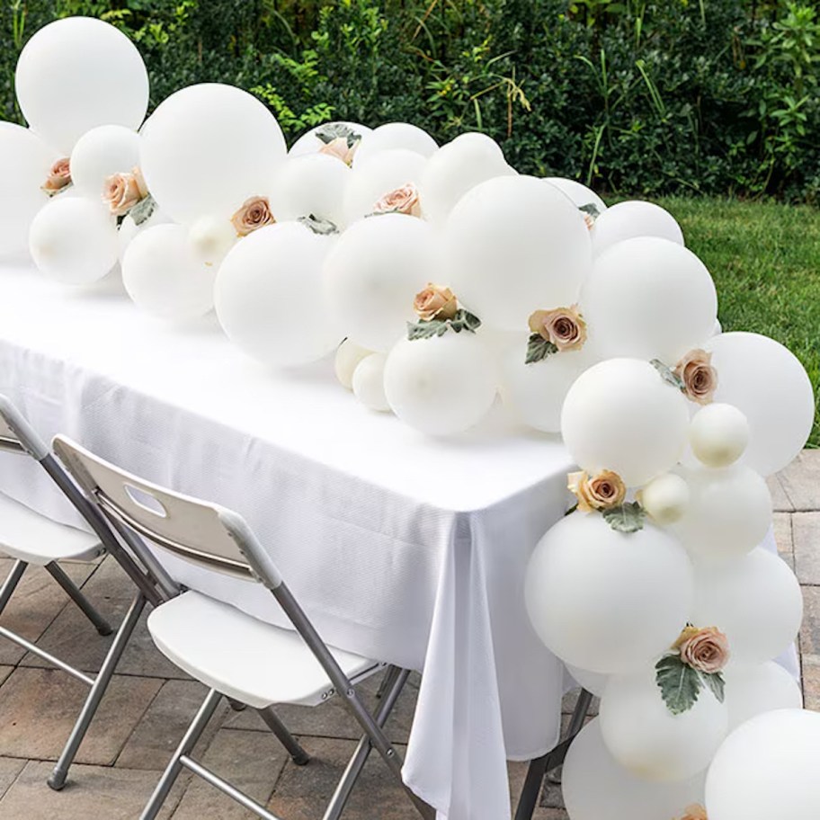 white balloon garland with pink flowers on table