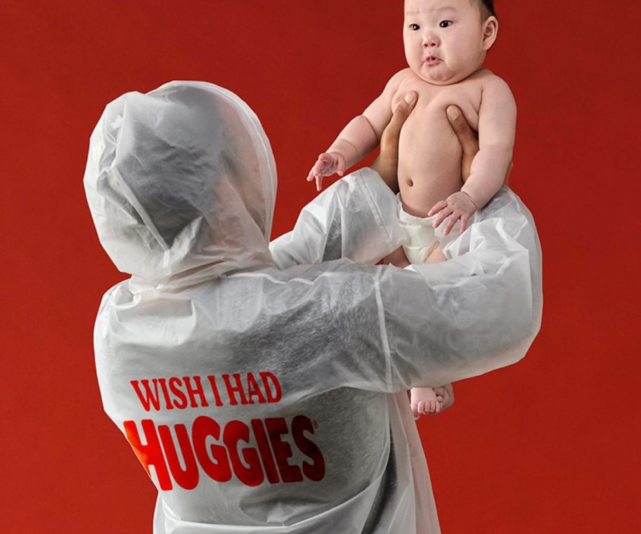 man holding up baby wearing poop poncho
