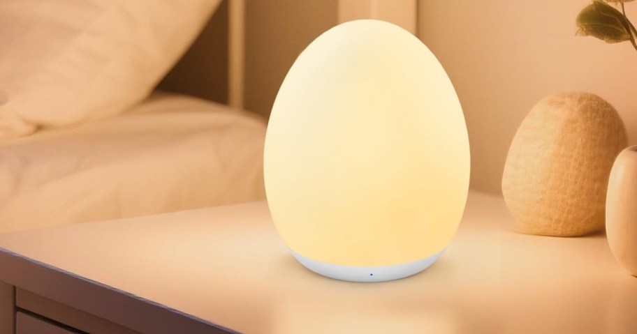 Softly glowing egg-shaped lamp on a bedside table.
