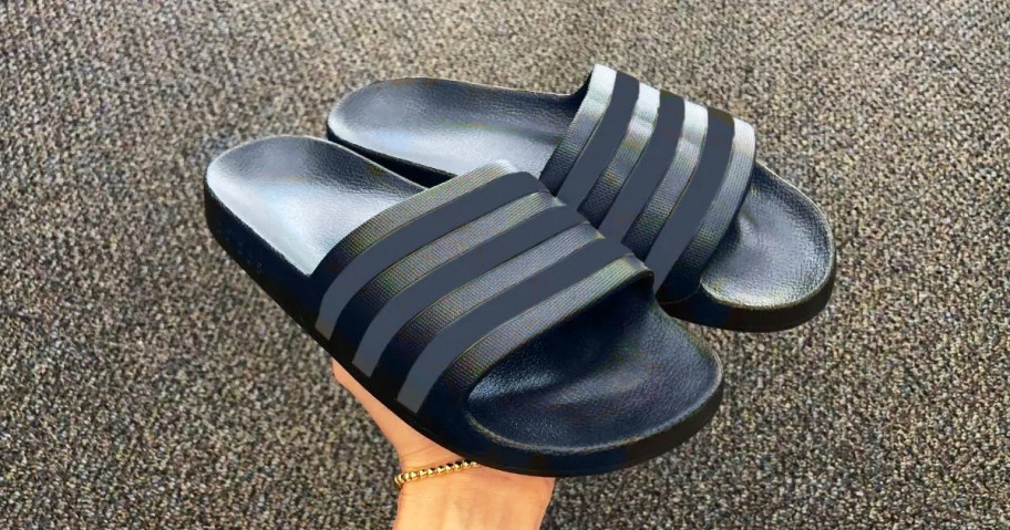 hand holding blue adidas slides