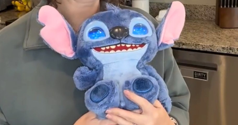 woman holding an interactive Disney Stitch plush toy