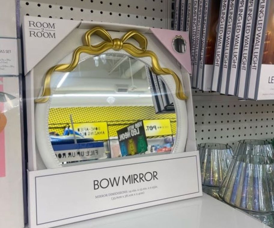 A mirror with a golden bow atop 