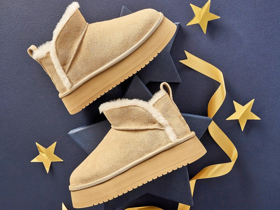 pair of short platform ugg boots with ribbons and stars around them