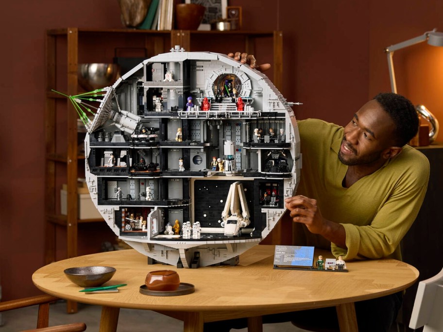 man assembling lego death star on table