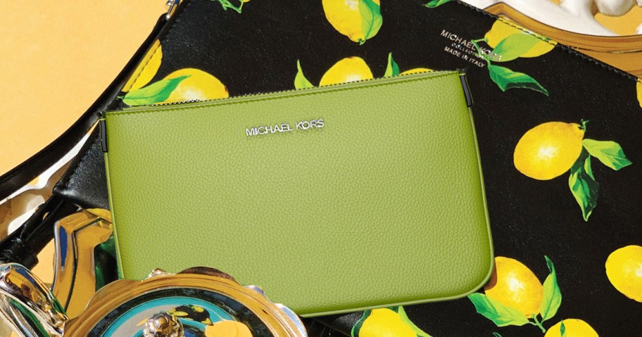 green michael kors wristlet on top of a lemon print bag