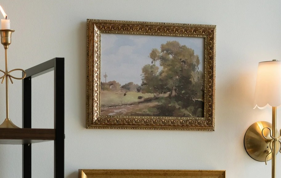 Gold framed picture of tree and landscape on wall 