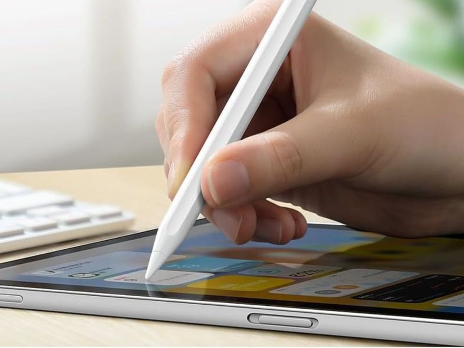 A person writing on an iPad with a stylus